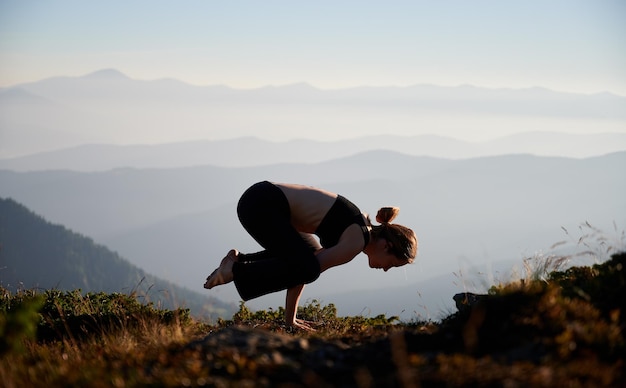 Young woman standing on hands in yoga exercise on nature