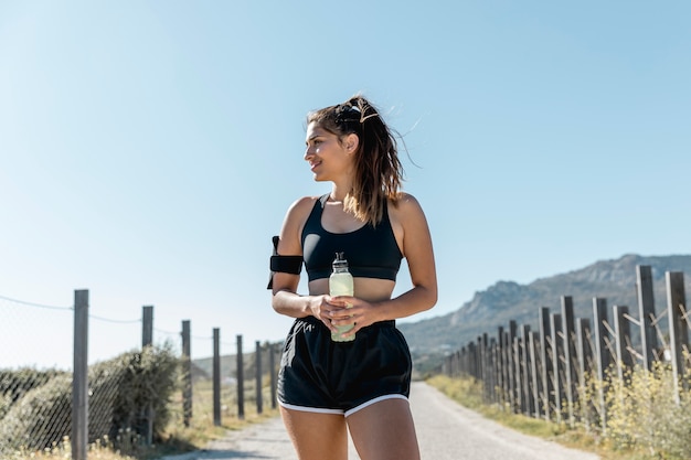 Free photo young woman standing and holding bottle of water