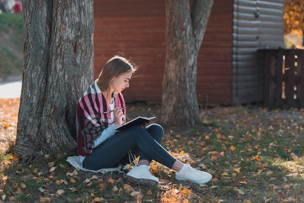 Young woman standing near a tree long shot