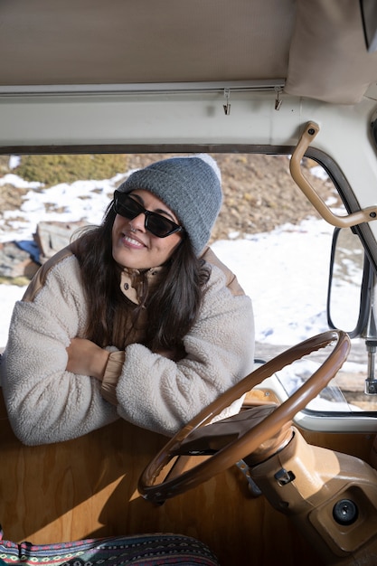 Young woman standing outside the camper van during winter trip