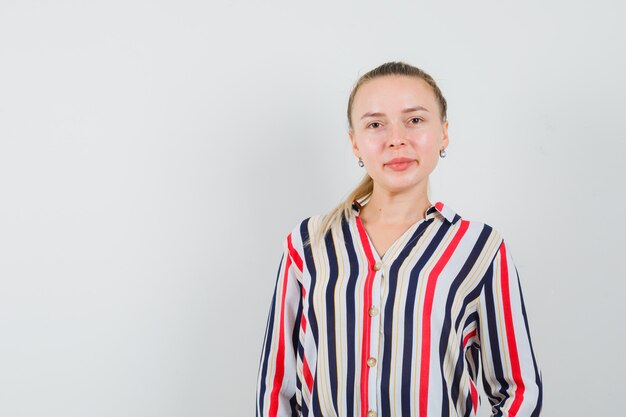 Young woman standing straight and smiling in striped blouse and looking confident