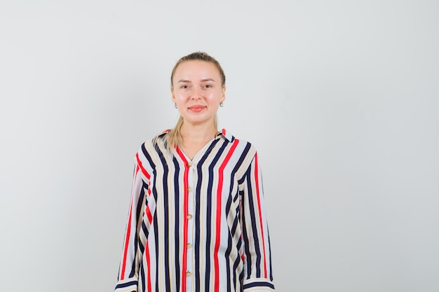 Young woman standing straight and smiling in striped blouse and looking happy