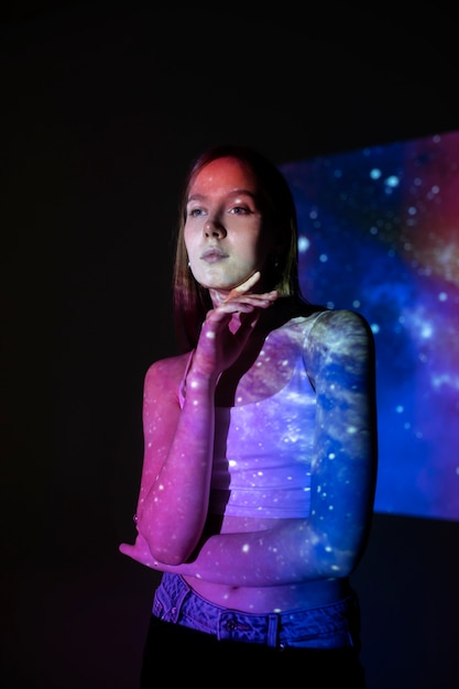 Free photo young woman standing in universe texture projection