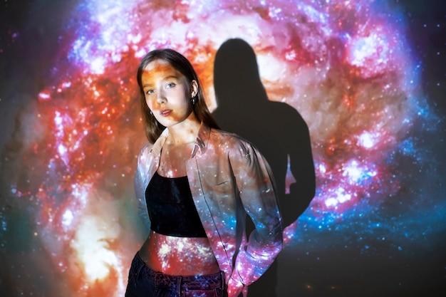 Free photo young woman standing in universe texture projection