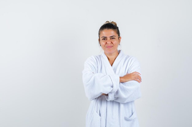 Young woman standing with crossed arms in bathrobe and looking confident