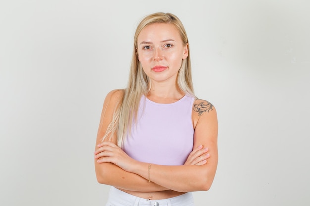 Young woman standing with crossed arms in singlet, mini skirt and looking confident.