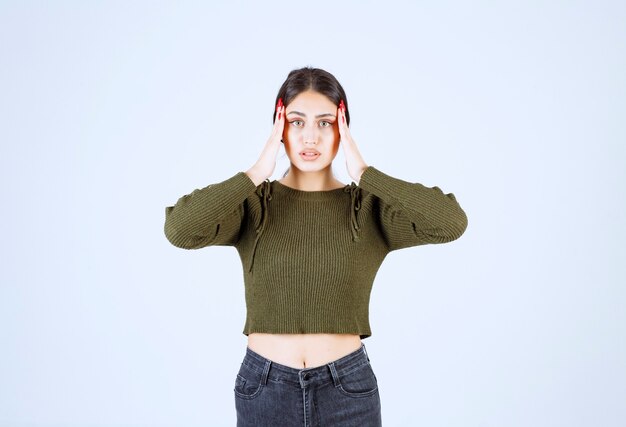 Young woman standing with painful headache on white background.