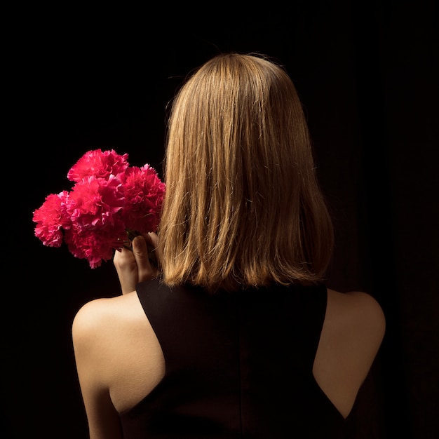 Young woman standing with pink flowers