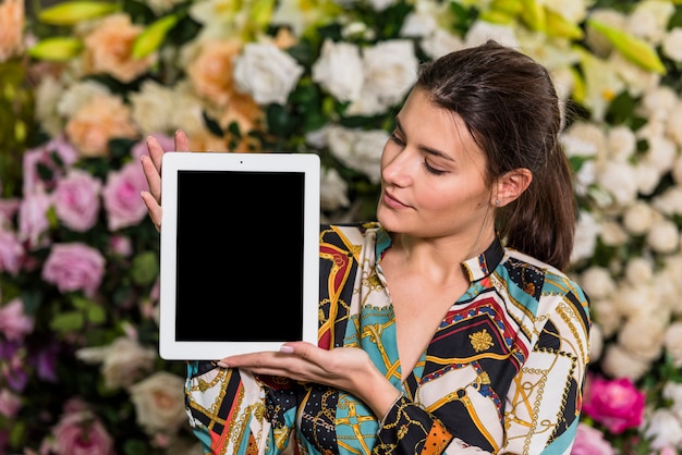 Free photo young woman standing with tablet in green house