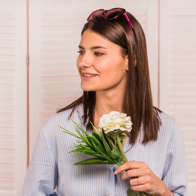 Young woman standing with white flower in hand