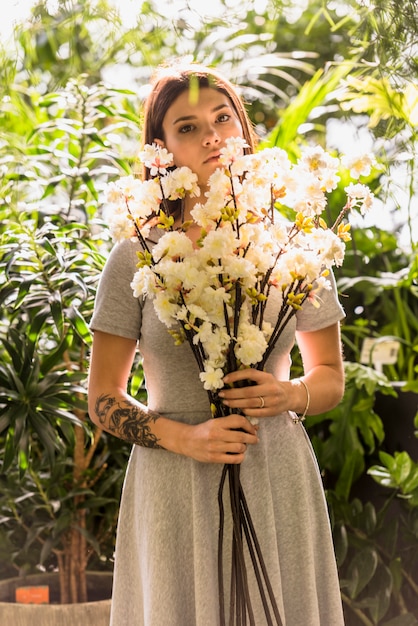 Free photo young woman standing with white flowers in hands