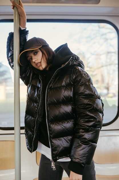 Young woman stands on the background of a window in public transport