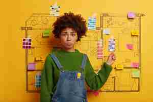 Free photo young woman stands next to house design sketch ready for renovation