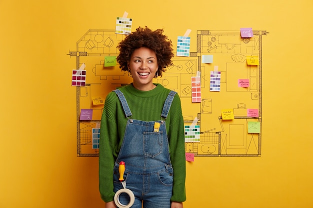 Young woman stands next to house design sketch ready for renovation