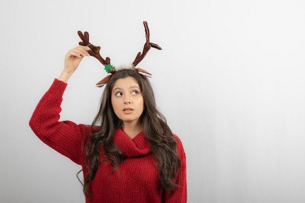 Free Photo a young woman stands with a headband in the form of christmas horns . 