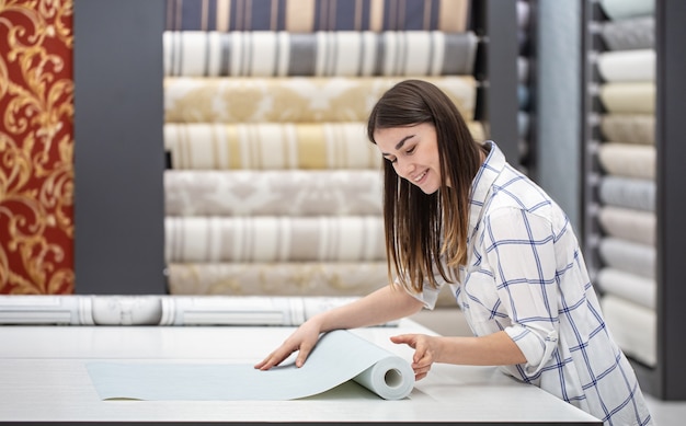 Free photo a young woman in a store chooses wallpaper for her home. concept of repair and shopping.