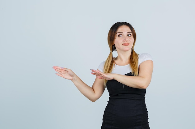 Young woman stretching hands toward left and looking cute