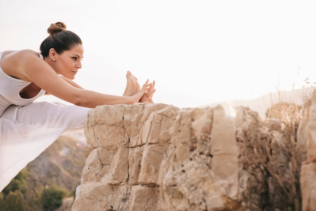 Free photo young woman stretching leg outdoors