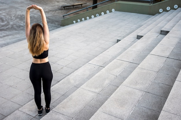 Free photo young woman stretching at the street