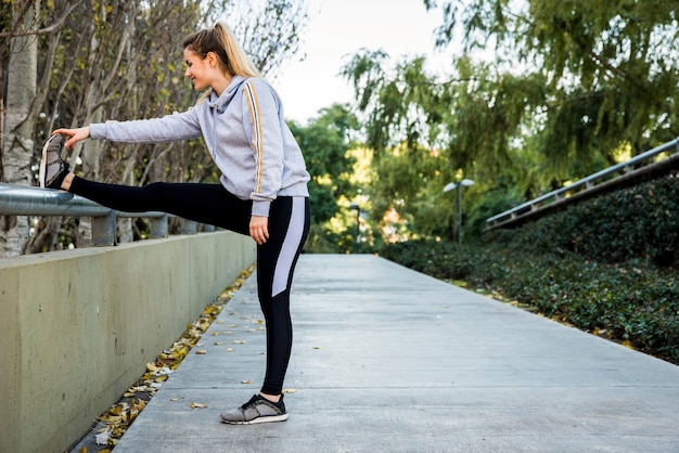 Free photo young woman stretching at the street