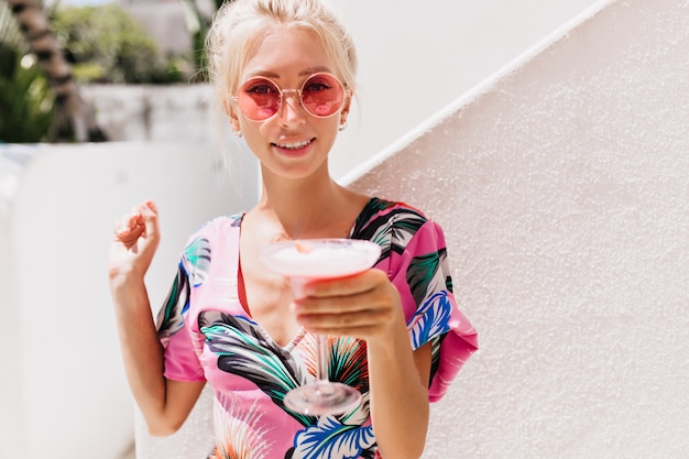 young woman in stylish clothes drinking cocktail in summer day.