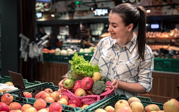 Young woman in a supermarket with vegetables and fruits buying groceries