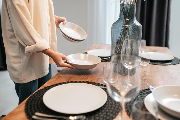 Young woman in a swhite shirt putting plates on the table