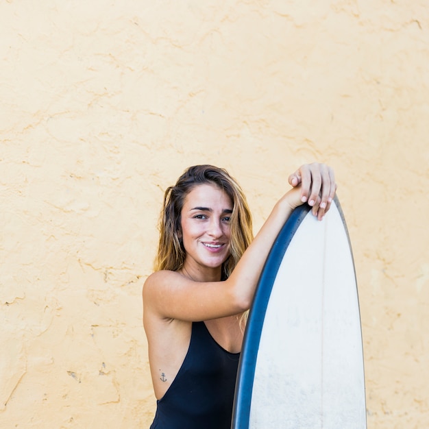 Free photo young woman in swimsuit with surfboard at wall