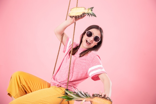 Free photo young woman on a swing on a pink