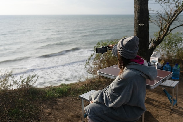 Free Photo young woman takes a photo on a smartphone of the seascape