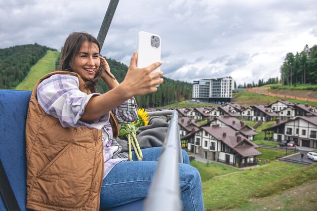 A young woman takes a selfie on a funicular in the mountains