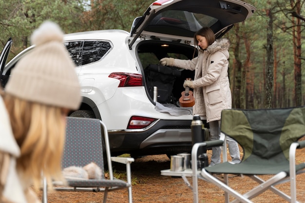 Free photo young woman taking a banjo from the car's trunk