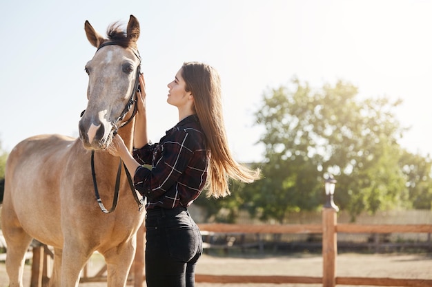 Free photo young woman taking care about horse on a farm run by her grandfather soon to become a stallion manager