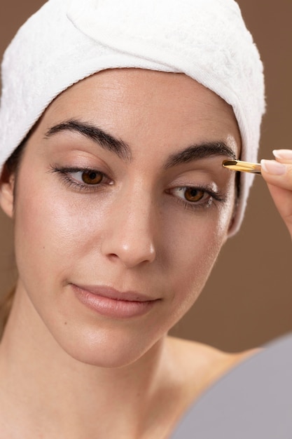 Free Photo young woman taking care of her eyebrows