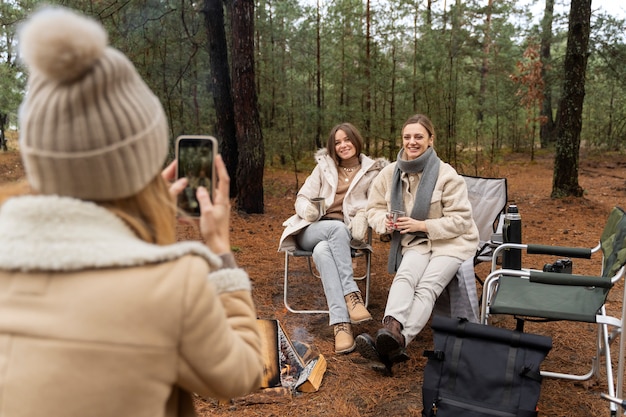 Free Photo young woman taking photo of her friends using her smartphone