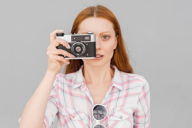 Free photo young woman taking photo with camera in studio