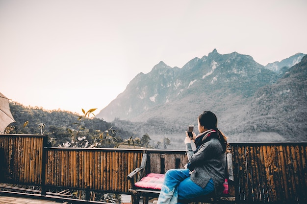 Free photo young woman taking photo with her phone of beautiful mountain view