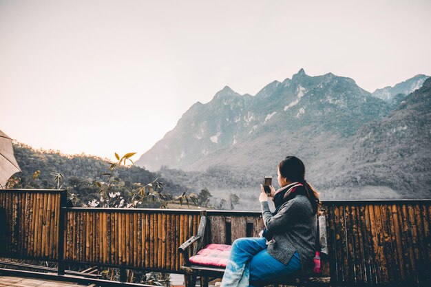 Young woman taking photo with her phone of beautiful mountain view