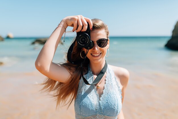 Young woman taking photos with photo camera on the beach