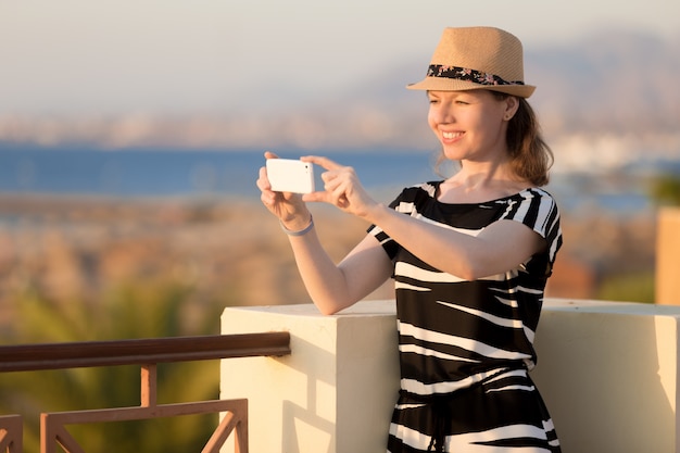 Young woman taking picture of sea town