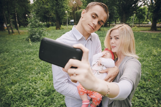 Free photo young woman taking a picture with her partner and her baby