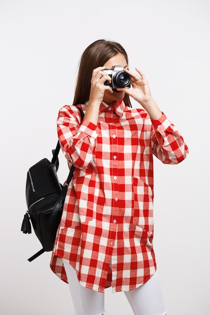 Free Photo young woman taking pictures on camera isolated on white wall