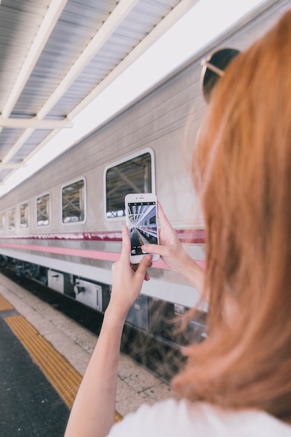 Free photo young woman taking shot of railway station