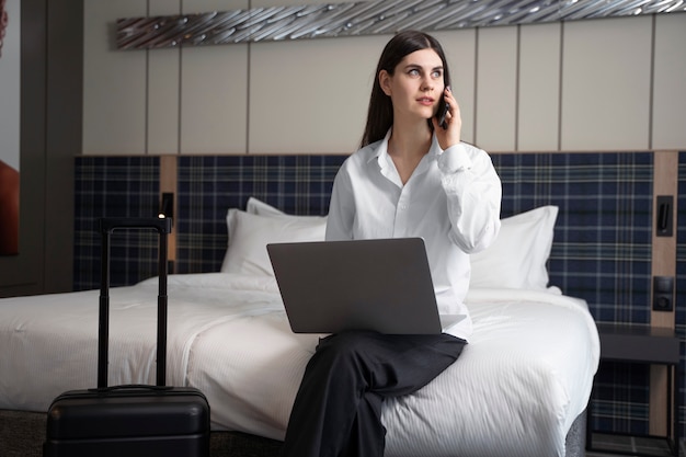 Free photo young woman talking on her smartphone in a hotel room