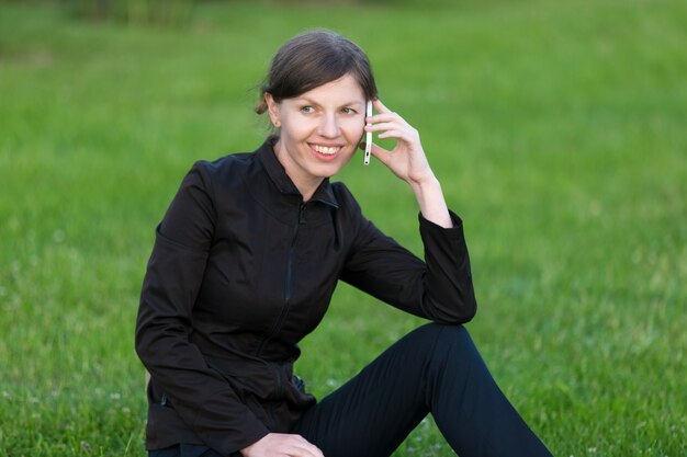 Young woman talking on mobile phone sitting on grass