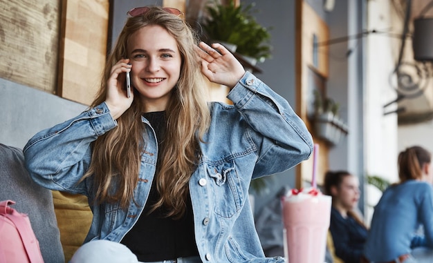 Free Photo young woman talking on mobile phone while sitting alone in cafe