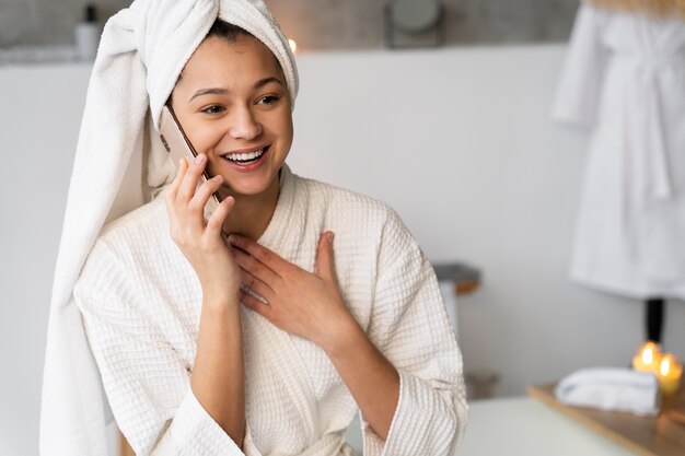 Young woman talking on the phone before taking a bath