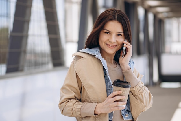 Young woman talking on the phone and drinking coffee