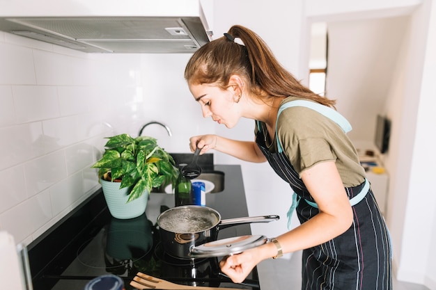 Young woman tasting the soup in the kitchen