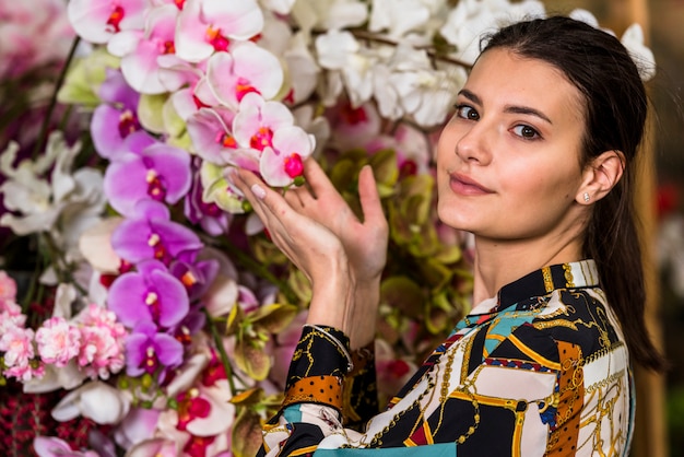 Free photo young woman touching flowers in green house